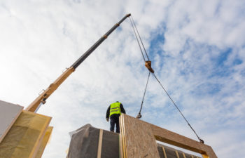 Roofer builder worker with crane installing structural Insulated Panels SIP. Building new modular energy-efficient house